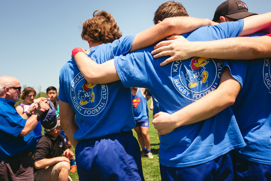 Three KU Men's Rugby players stand arm-in-arm