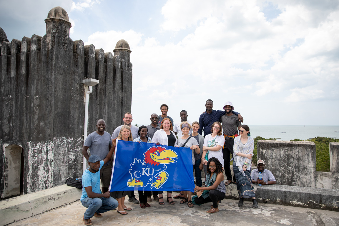 Students abroad in Tanzania posing with a Jayhawk flag.